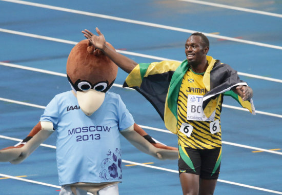 El plusmarquista jamaicano Usain Bolt (d) celebra su triunfo en los 100 metros planos junto a la mascota de los Juegos Mundiales de Mosc.