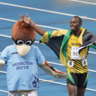 El plusmarquista jamaicano Usain Bolt (d) celebra su triunfo en los 100 metros planos junto a la mascota de los Juegos Mundiales de Mosc.