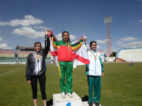 La atleta capitalina Ibeth Quevedo celebra en el podio con la bandera de Chuquisaca tras ganar una prueba.