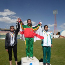 La atleta capitalina Ibeth Quevedo celebra en el podio con la bandera de Chuquisaca tras ganar una prueba.