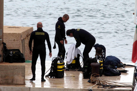 RESCATE. Varios buzos de un equipo de rescate permanecen en el puerto de la isla de Lampedusa antes de iniciar un operativo.