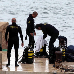 RESCATE. Varios buzos de un equipo de rescate permanecen en el puerto de la isla de Lampedusa antes de iniciar un operativo.