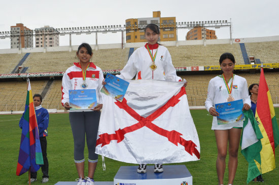 La capitalina Seln Zurita (d) celebra en el podio tras vencer en Salto de Longitud; al lado, los chuquisaqueos Ren Daza (c) y Elas Paco recibieron sus medallas.