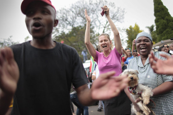 TRIBUTO. Un grupo de personas cantan y bailan en el exterior de la casa del ex presidente sudafricano Nelson Mandela en Johannesburgo.