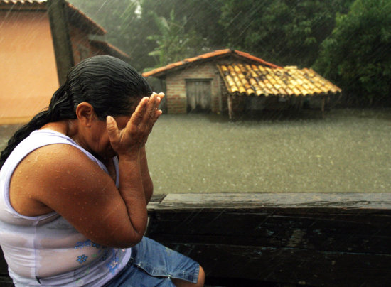 DESASTRE. Una mujer llora de impotencia frente a su casa inundada mientras la lluvia no deja de caer.