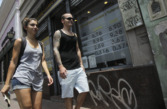 SUBIDA. Una pareja camina frente a la entrada a una casa de cambio en Buenos Aires.