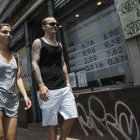 SUBIDA. Una pareja camina frente a la entrada a una casa de cambio en Buenos Aires.