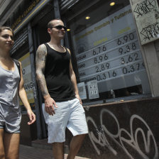 SUBIDA. Una pareja camina frente a la entrada a una casa de cambio en Buenos Aires.