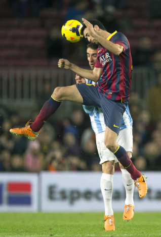 El volante del Barcelona Sergio Busquets (d) salta por el baln ante la presin de un jugador rival.