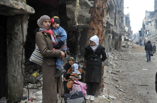 CONFLICTO. Varios residentes de Homs mientras esperan para ser evacuados de un campamento ante el recrudecimiento de la violencia.