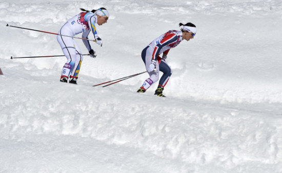 Marit Bjoergen (d) aport con una medalla de oro para el liderato de Noruega en la prueba de esquiatln.