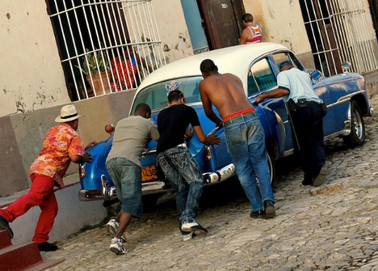 BLOQUEO. Cubanos intentan mover un automvil con ms de medio siglo de uso.