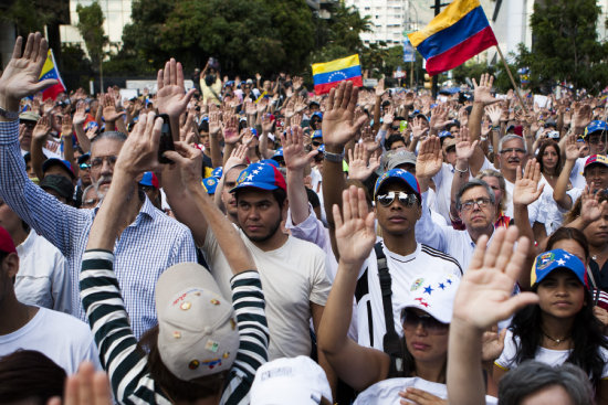 CONVOCATORIA. Un grupo de personas levanta sus manos en una avenida de Caracas.