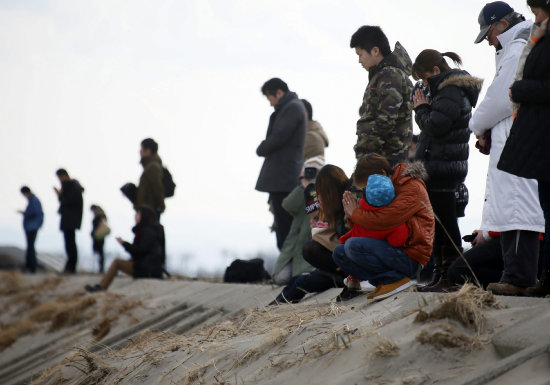 RECUERDO. Varias personas guardan un minuto de silencio por el tsunami en Sendai.