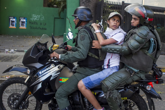 DETENIDOS. Policas venezolanos en moto detienen a un manifestante durante una protesta.