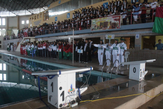 El acto inaugural de ayer, en la piscina de El Rollo; abajo, la partida de un grupo de nadadoras.