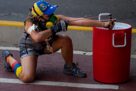 PROTESTAS. Una manifestante opositora lanza piedras contra un grupo de policas en Caracas.