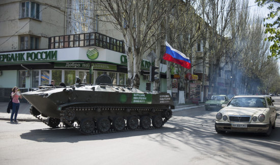 TENSIN. Un vehculo blindado para el transporte de tropas con una bandera rusa recorre una calle de Slaviansk, Ucrania.