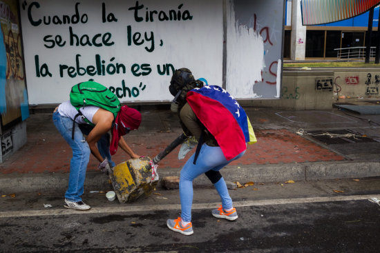 PROTESTA. Manifestantes opositores tratan de instalar una barricada en Caracas.