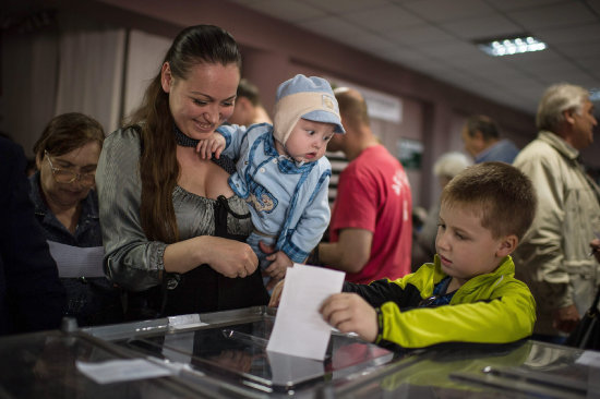 REFERNDUM. Una mujer emite su voto junto a su hijo en un centro electoral de la rebelde Lugansk, durante la consulta popular de ayer.