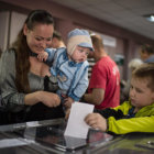 REFERNDUM. Una mujer emite su voto junto a su hijo en un centro electoral de la rebelde Lugansk, durante la consulta popular de ayer.