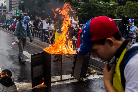 PROTESTA. Manifestantes opositores prenden fuego a una barricada en Caracas.