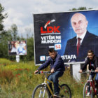 CAMPAA. Unos nios montan en bicicleta cerca de un cartel electoral en Kosovo.