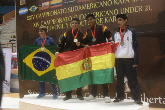 El boliviano Mohamed Dames celebra en el podio tras colgarse la medalla de oro; al lado, otro de los bolivianos que gan una medalla de plata.