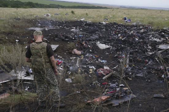 RESCATE. Un rebelde ucraniano observa los restos del avin de Malasyan Airlines durante el rescate de los cuerpos de las vctimas.