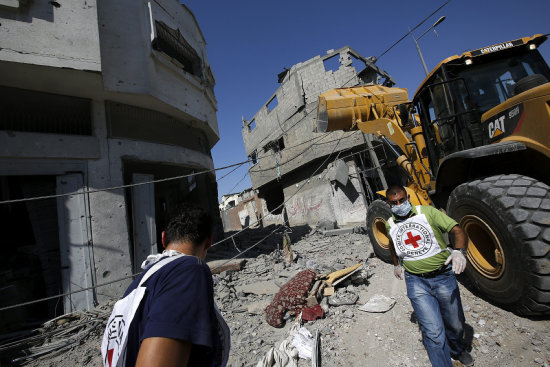 DESTRUCCIN. Miembros de la Cruz Roja caminan por una calle llena de escombros en un barrio de la ciudad de Gaza.