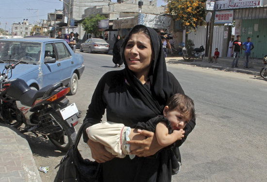 GUERRA. Una mujer palestina lleva a un nio en brazos despus de un ataque areo israel sobre la localidad de Rafah, en el sur de Gaza.