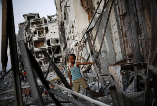 DESASTRE. Un niño palestino juega en los escombros de una torre metálica en la Franza de Gaza.