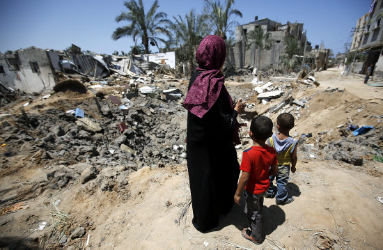 BOMBARDEO. Una familia observa los destrozos de su casa en la ciudad de Deir Al-Balah, Franja de Gaza, ayer mircoles.