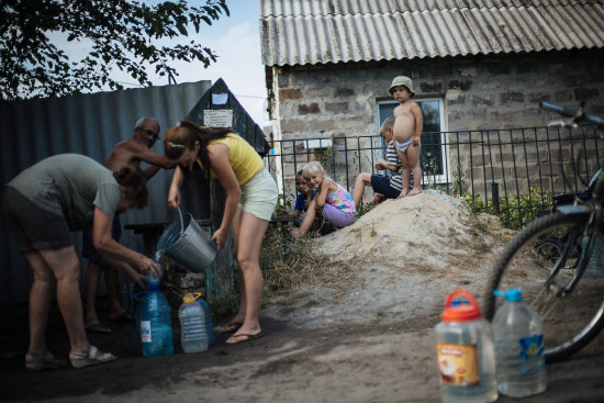 CRISIS. Ciudadanos del este de Ucrania intentan abastecerse de agua en una fuente, ante el recrudecimiento de la escasez de ese lquido vital.