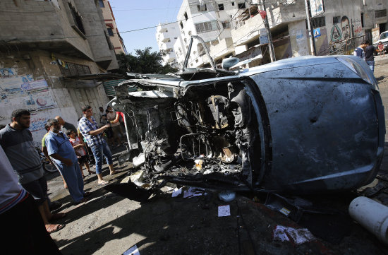 Bombardeos. Palestinos observan un automvil destrozado que fue alcanzado por una bomba en una calle de Gaza.