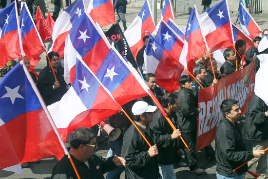 PROTESTAS. Manifestantes ondean banderas durante una marcha nacional en Chile.