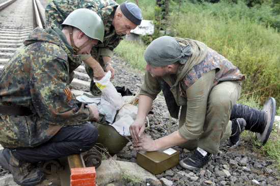 ALERTA. Un grupo de especialistas del escuadrn de explosivos desactiva una mina cerca de una va del tren en Ilovaisk, este de Ucrania.