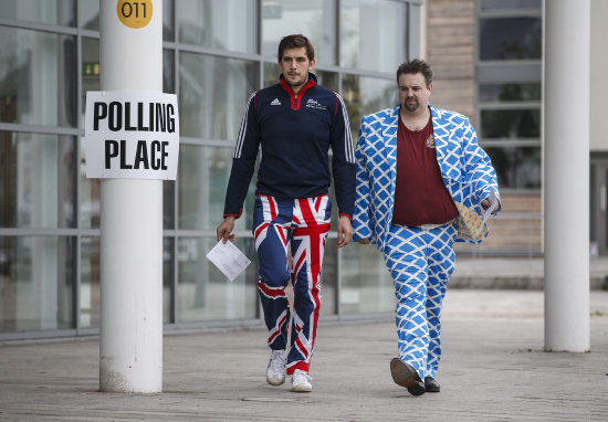 CONSULTA. Un hombre vestido con unos pantalones de la bandera del Reino Unido y otro con los colores de Escocia asisten a votar, ayer.