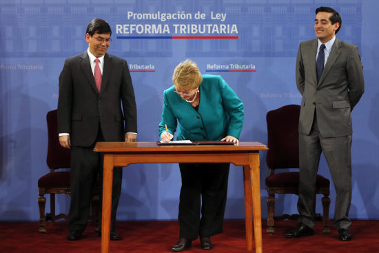 PROMULGACIN. La presidenta de Chile, Michelle Bachelet firma junto a dos de sus ministros la ley de reforma impositiva.