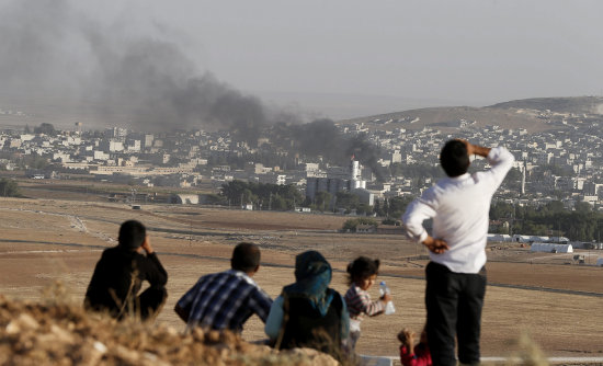 COMBATES. Residentes turcos observan un bombardeo aliado sobre un barrio de la ciudad kurda de Kobani, en Siria.