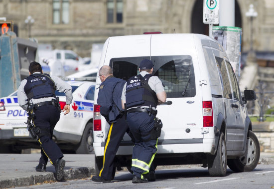 ATAQUE. Policas canadienses se cubren tras un vehculo durante el tiroteo protagonizado por un individuo cerca del Parlamento en Ottawa.