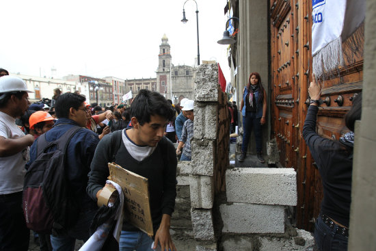 PROTESTAS. Manifestantes intentan construir una barricada en la plaza El Zcalo.