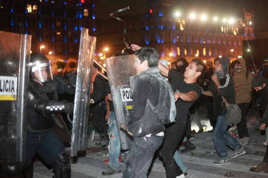 PROTESTAS. Un grupo de manifestantes encapuchados se enfrentan con miembros de la Polica en el Zcalo de Ciudad de Mxico.