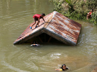 INUNDACIN. Una nia filipina se encarama a un tejado y otras nadan tras la crecida de un ro.