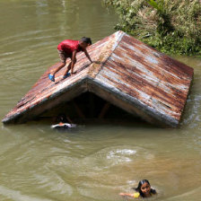 INUNDACIN. Una nia filipina se encarama a un tejado y otras nadan tras la crecida de un ro.