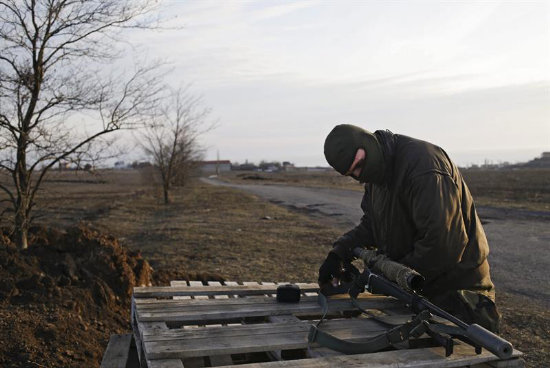 CALMA. Un miembro de las fuerzas ucranianas prepara su rifle mientras hace guardia en la localidad de Shyrokino, cerca de Mariupol.